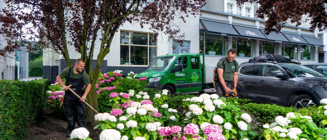 Hoveniers verzorgen de plantvakken bij het hotel