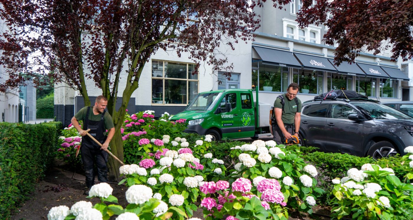 Hoveniers verzorgen de plantvakken bij het hotel