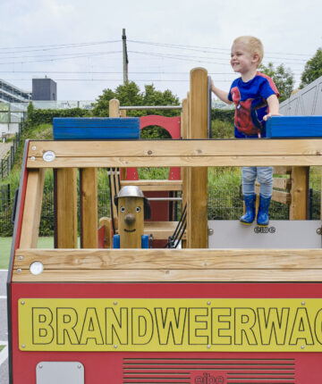 Een jongetje speelt op het speeltoestel in de brandweer speeltuin.